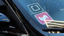 FILE - In this Tuesday, Jan. 12, 2016, file photo, a driver displaying Lyft and Uber stickers on his front windshield drops off a customer in downtown Los Angeles.