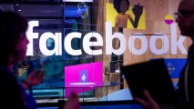 Conference workers speak in front of a demo booth at Facebook