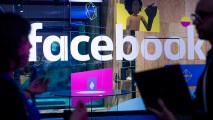 FILE - In this April 18, 2017, file photo, conference workers speak in front of a demo booth at Facebook