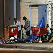 LOS ANGELES, CA - OCTOBER 12:  A homeless couple gets up before dawn to dismantle their encampment before businesses open October 12, 2007 in the downtown Skid Row area of Los Angeles, California. Los Angeles city officials recently settled a 2003 lawsuit