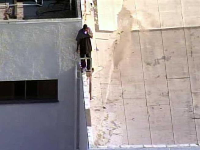 Officers wait for a man to come down from the roof of the Budweiser plant.