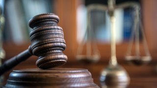 Mallet of the judge, books, scales of justice. Gray stone background, reflections on the floor, place for typography. Courtroom theme.