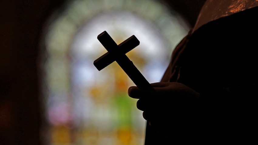 A crucifix and a stained glass window inside a Catholic Church.