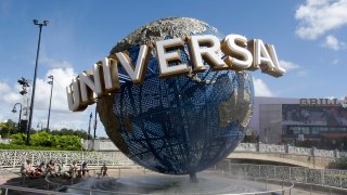 In this Oct. 22, 2015 file photo, park guests relax and cool off with a water mist under the globe at Universal Studios City Walk in Orlando, Fla.