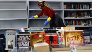A worker disinfects bookshelves at the library of the Evangelical School, in Loueizeh, east of Beirut, Lebanon, Monday, March 2, 2020.
