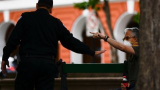 Gustavo Cuevas del Valle, right, who lives on Luna street in Old San Juan, argues with a police officer that asked him not to occupy the benches during a lock down imposed by the government to prevent a spread of the new coronavirus in San Juan, Puerto Rico, Tuesday, March 17, 2020.