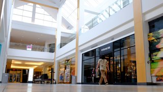 A visitor walks in an empty hallway at The Fashion Mall at Keystone, Wednesday, March 18, 2020, in Indianapolis.