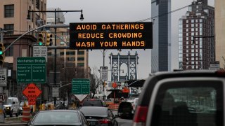 The Manhattan bridge is seen in the background of a flashing sign urging commuters to avoid gatherings, reduce crowding and to wash hands in the Brooklyn borough of New York