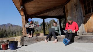 Members of a family gather outside, some using computers, during the coronavirus pandemic