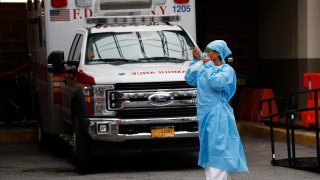 An emergency room nurse dons her face protectors after taking a break in a driveway for ambulances and emergency medical services vehicles outside Brooklyn Hospital Center's emergency room