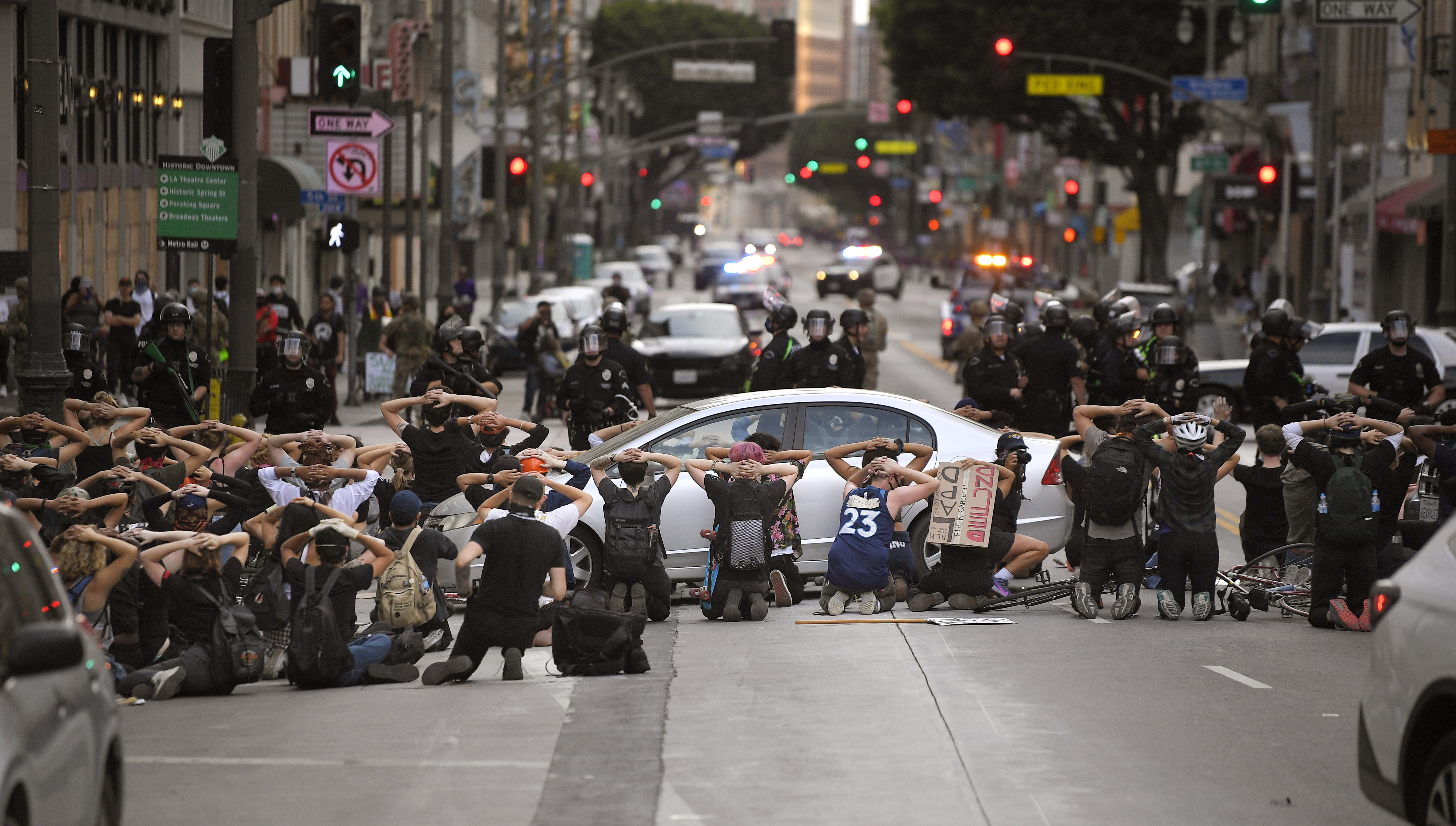 Demonstrators put their hands behind their heads before being taken into custody after the city’s curfew went into effect, June 2, 2020, in Los Angeles.