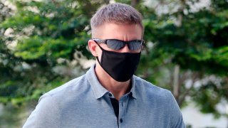 In this May 13, 2020, photo, Brian Dugan Yeargan, wearing a face mask and sunglasses, walks outside the Singapore State Court in Singapore. The 44-year-old American pilot has been jailed for four weeks for breaching a quarantine order in Singapore.
