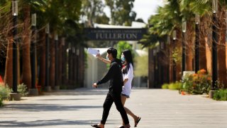 FULLERTON-CA-APRIL 21, 2020: Cal State University Fullerton student Linh Trinh, 21, right, and her boyfriend Tan Nguyen, 21, walk around a deserted CSUF campus on Tuesday, April 21, 2020. (Christina House / Los Angeles Times via Getty Images)