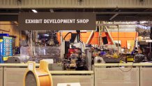 "exhibit development shop" sign above a messy workshop full of equipment