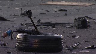 A car tire and debris lay on the road following a car crash.