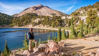 Stock photograph of hiker looking at view in Lassen Volcanic National Park on a sunny day, with Lake Helen and Lassen Peak in the background. (Stock photograph of hiker looking at view in Lassen Volcanic National Park on a sunny day, with Lake Helen a