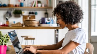 Woman using laptop at table at home