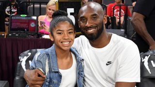 Kobe and Gianna Bryant hugging, smiling at the camera sitting down