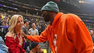 Kobe Bryant speaks with Lakers President Jeanie Buss during a game.