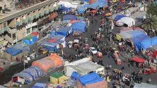 This picture taken on Jan. 17, 2020, shows a view of vehicles and tuktuks — motorized rickshaws — driving past tents at the anti-government protest sit-in at the Iraqi capital’s central Tahrir Square.
