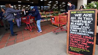 A sign posted in front of a Trader Joe’s reminds shopppers of purchase limits as handwipes are handed out to shoppers, some wearing facemasks from fear of the coronavirus on March 18, 2020 in Monrovia, California. (Photo by Frederic J. BROWN / AFP) (Photo by FREDERIC J. BROWN/AFP via Getty Images)