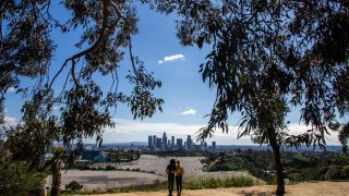 A couple looks at the downtown Los Angeles skyline from Elysian Park in Los Angeles on March 21, 2020. (Photo by Apu GOMES / AFP) (Photo by APU GOMES/AFP via Getty Images)