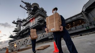 Sailors assigned to the aircraft carrier USS Theodore Roosevelt (CVN 71) carry food supply boxes
