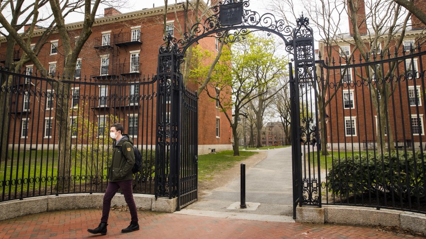 A pedestrian wearing a protective mask exits Harvard Yard on the closed Harvard University campus in Cambridge, Massachusetts, U.S., on Monday, April 20, 2020. College financial aid offices are bracing for a spike in appeals from students finding that the aid packages they were offered for next year are no longer enough after the coronavirus pandemic cost their parents jobs or income.