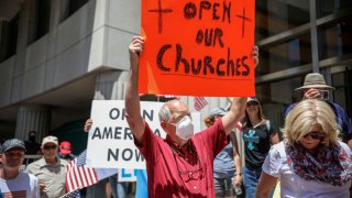 Demonstrators holding signs demanding their church be allowed to reopen rally to re-open California and to protest the state's stay-at-home directives, May 1, 2020, in San Diego, California. Rallies have been held at several state capitols across the country as protesters express their frustration with stay-at-home orders that are meant to stem the spread of the novel coronavirus.