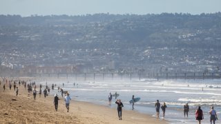 People walk on Manhattan Beach May 13, 2020 in Southern California.