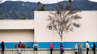 People wait in line outside a DMV office.