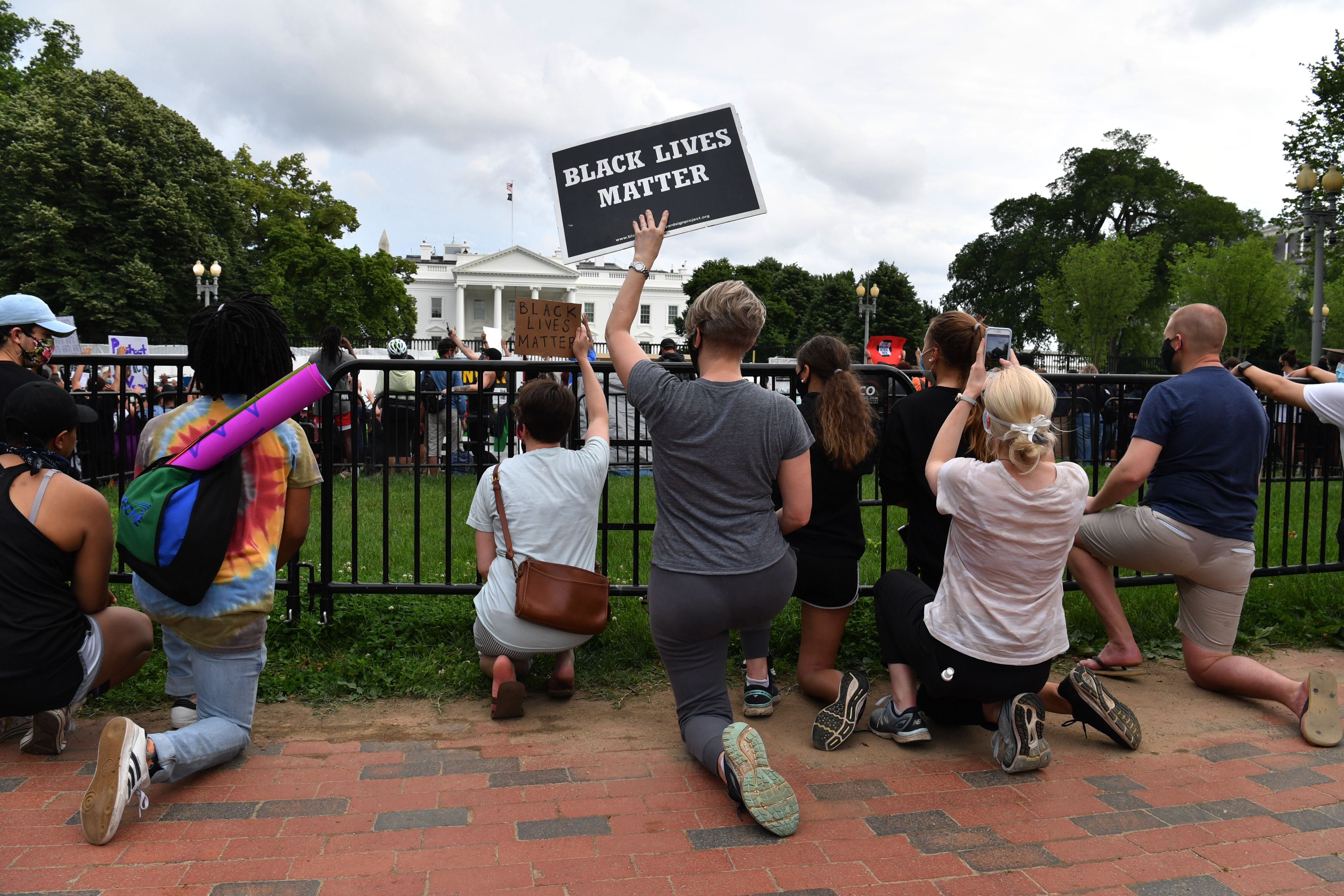 Protesters kneel behind a gate during a demonstration outside the White House in Washington, DC, on May 29, 2020, over the death of George Floyd, a black man who died after a white policeman kneeled on his neck for several minutes.