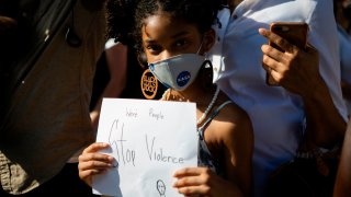 A young girl wearing a facemask holds a sign during a rally in Coral Gables, Florida on May 30, 2020 in response to the recent death of George Floyd, an unarmed black man who died while being arrested and pinned to the ground by a Minneapolis police officer.