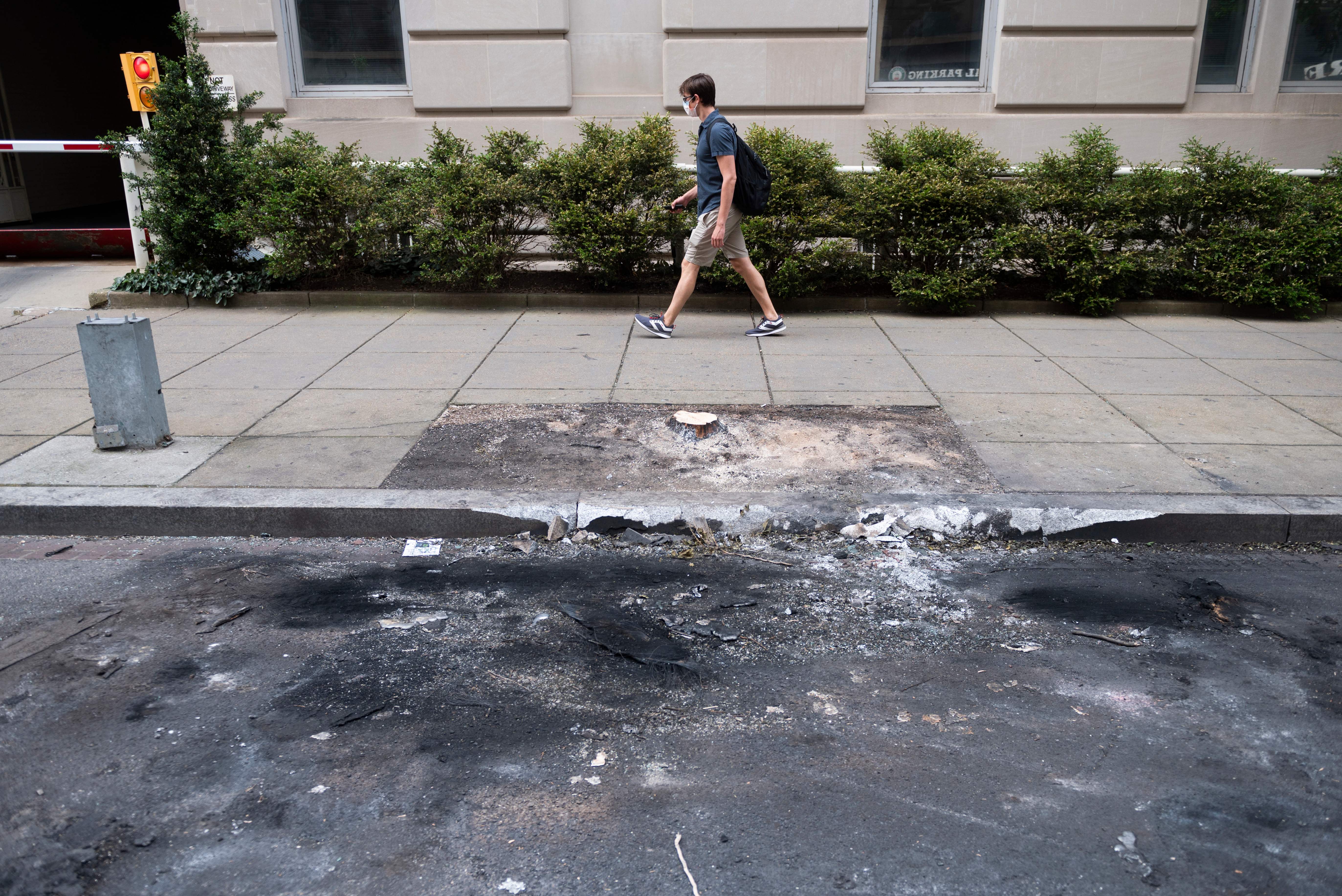 A man walks past the burned remains of a car that was towed away, after the unrest from the past few nights, in Washington, D.C., June 2, 2020.