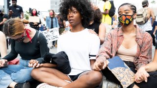 Demonstrators sit holding hands during a march in response to George Floyd's death on June 2, 2020 in Los Angeles, California.