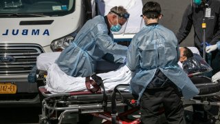 Medics and hospital workers tend to a COVID-19 patient outside the Montefiore Medical Center Moses Campus on April 7, 2020 in New York City.