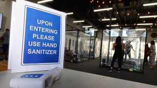 A sign is pictured as people exercise at Inspire South Bay Fitness behind plastic sheets in their workout pods while observing social distancing on June 15, 2020 in Redondo Beach, California, as the gym reopens today under California’s coronavirus Phase 3 reopening guidelines.
