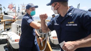 File Image: United States Coast Guard Lieutenant Caroline Miller elbow bumps Commander Marshall Newberry aboard a patrol boat following monitoring of oil tankers anchored near the ports of Long Beach and Los Angeles amid the coronavirus pandemic on May 1, 2020 off the coast of Long Beach, California.