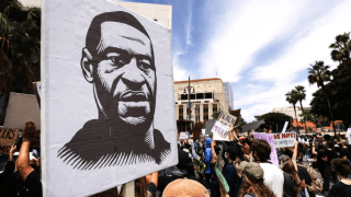 A protester holds a sign with an image of George Floyd during a peaceful demonstration over Floyd’s death outside LAPD headquarters on June 2, 2020 in Los Angeles, California.