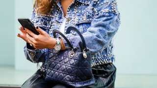 A woman holds a cell phone on a street in Paris, France.