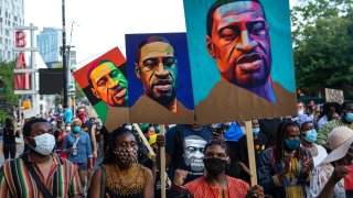 Pedestrians carry posters depicting George Floyd during a Juneteenth protest march on June 19, 2020, in the Brooklyn borough of New York City.