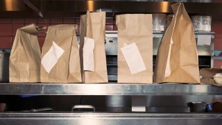 Food in take out bags with receipts, sitting on restaurant shelf