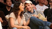 Ashton Kutcher and Mila Kunis smile during basketball game