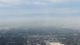 File Image: Skyscrapers and city surrounding downtown LA with a very thick smog layer viewed form an airplane