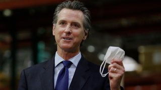 Gov. Gavin Newsom displays a face mask as he urges people to wear them to fight the spread of the coronavirus during a news conference in Rancho Cordova, Calif., Friday, June 26, 2020. Newsom said he wants Imperial County in Southern California to reimpose a stay-at-home order amid a surge in positive coronavirus tests.