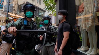 Riot police form a line as they check pedestrians gathered in the Central district of Hong Kong, Wednesday, May 27, 2020. Hong Kong police massed outside the legislature complex Wednesday, ahead of debate on a bill that would criminalize abuse of the Chinese national anthem in the semi-autonomous city.