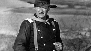 In this undated photo, John Wayne appears during the filming of "The Horse Soldiers." In the latest move to change place names in light of U.S. racial history, leaders of Orange County’s Democratic Party are pushing to drop film legend Wayne’s name, statue and other likenesses from the county’s airport because of his racist and bigoted comments.