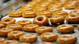 Krispy Kreme Original Glazed Donuts on a conveyor belt.