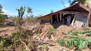 Debris from floods caused by Typhoon Phanfone surround a damaged house in Balasan Town, Iloilo province, central Philippines on Thursday Dec. 26, 2019.