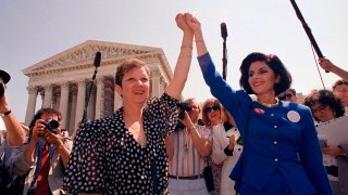 In this April 26, 1989, file photo, Norma McCorvey, Jane Roe in the 1973 court case, left, and her attorney Gloria Allred hold hands as they leave the Supreme Court building in Washington after sitting in while the court listened to arguments in a Missouri abortion case.